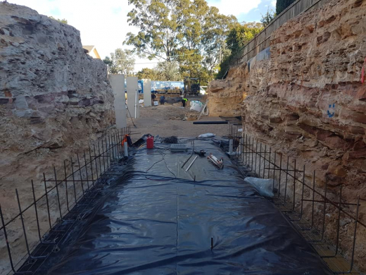 Residential excavation polythene sheets on a residential property excavation with sandstone walls